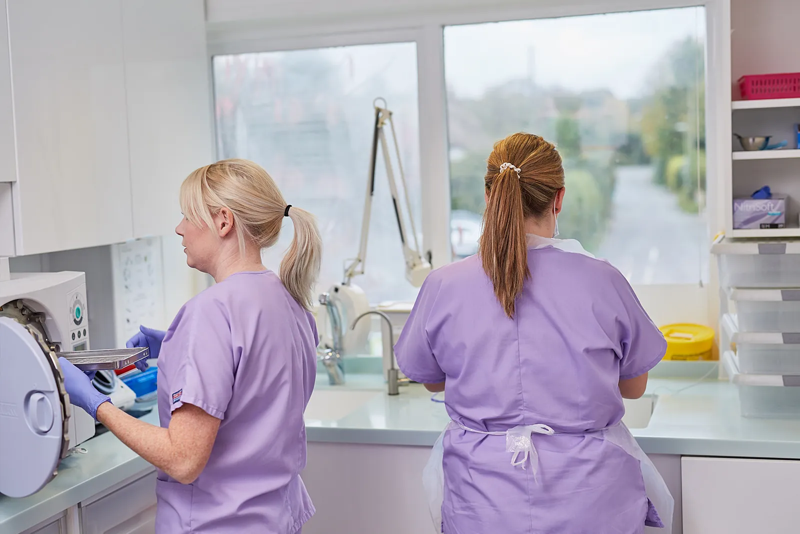 Two dental nurses in lilac scrubs working in the decontamination room