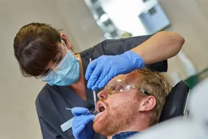 A dental hygienist cleaning a patient's teeth during a hygiene appointment