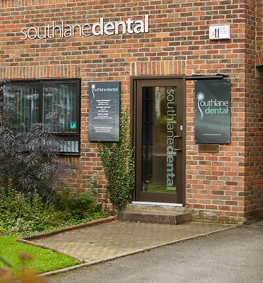 The front entrance of South Lane Dental with its glass door and signage