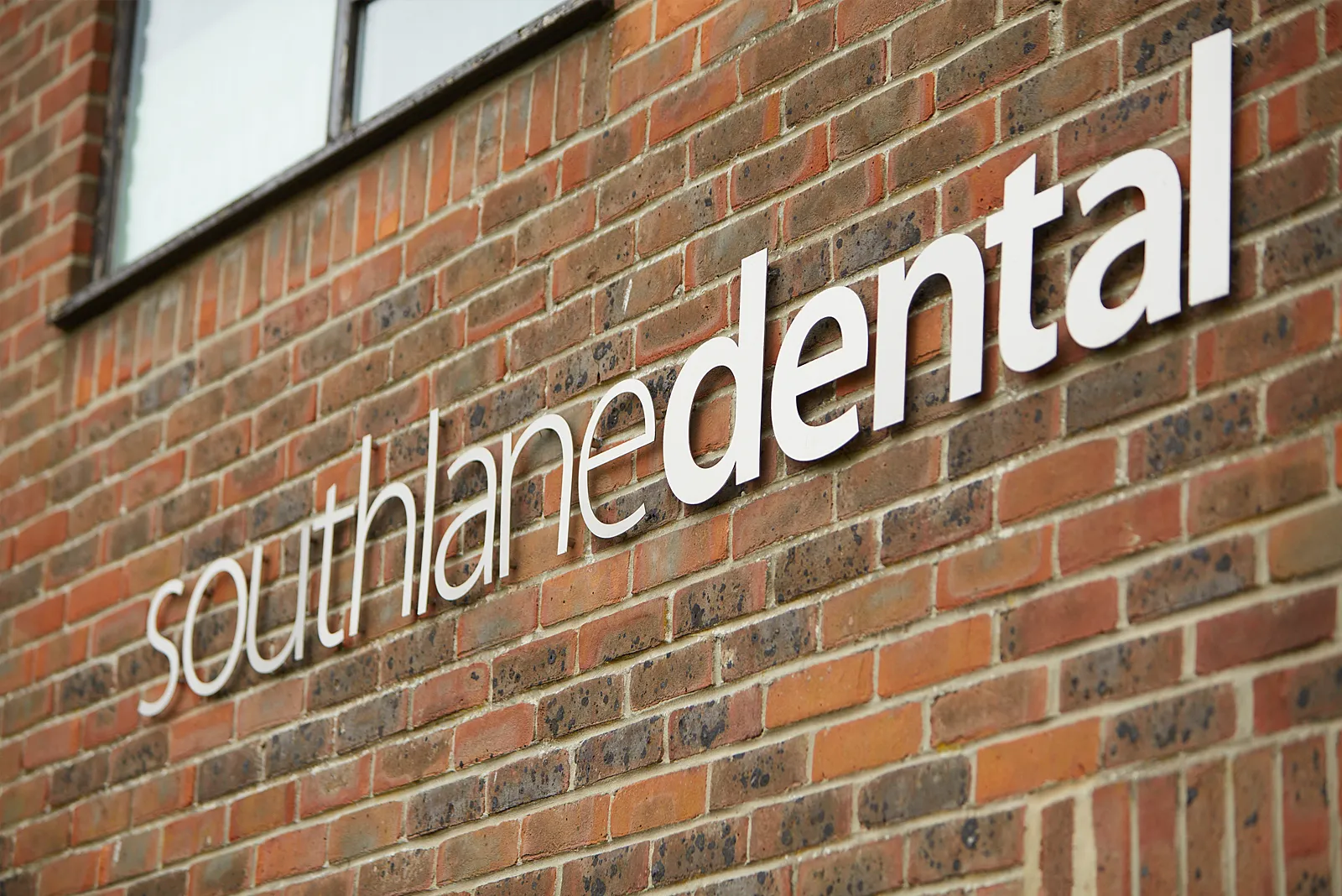 The South Lane Dental sign in raised letters on the brick front of the practice