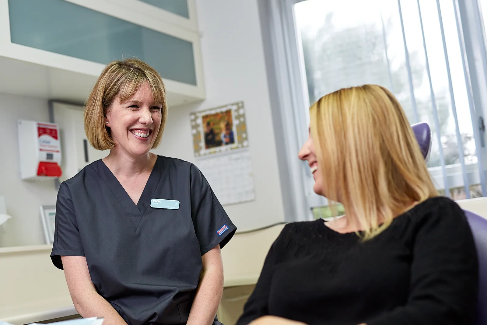 A team member in navy scrubs chatting with a patient in the surgery